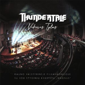 Matoma didelė koncertų salė, pilna žiūrovų tiek pirmoje salės dalyje, tiek balkonuose. Scena apšviesta ryškiomis, į viršų kylančiomis šviesų juostomis, suteikiančiomis dinamikos ir dramatizmo. Centre – grupė, grojanti ant scenos. Nors konkrečių žmonių neidentifikuojama, matyti keli muzikantai su instrumentais, scenos atmosfera yra gyva ir energinga. Nuotrauka daryta iš aukštai, su plataus kampo optika, todėl salė atrodo išlenkta, o vaizdas – įtraukiantis ir erdvinis. Šviesos ir dūmų efektai kuria koncertinę, šiek tiek epinę nuotaiką.