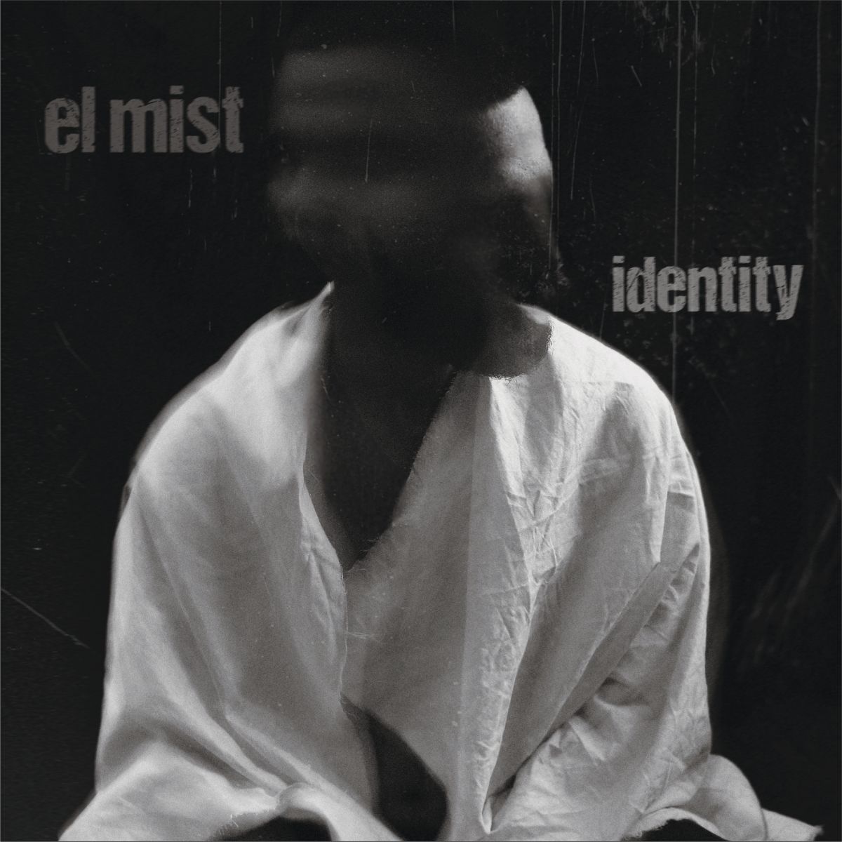 Juodai baltas vinilo albumo „Identity“ viršelis – centre sėdintis išsiliejusio veido žmogus baltu drabužiu, tamsiame fone, kairėje užrašas „el mist“, dešinėje „identity“. Atmosferiškas, minimalistinis dizainas su grūdėtos fotografijos efektu.